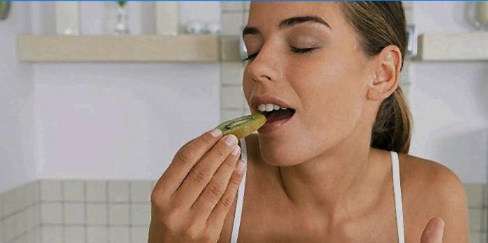 Kvinde spiser en sund kiwi