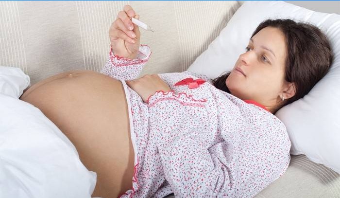 Gravid pige måler temperaturen