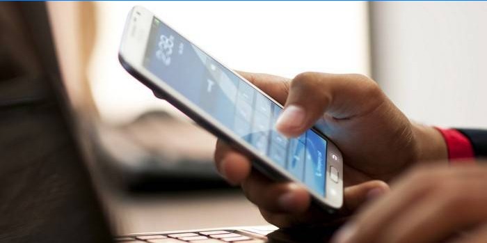 Fyren bag den bærbare computer med en smartphone i hånden