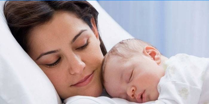 En baby sover på sin mors bryst