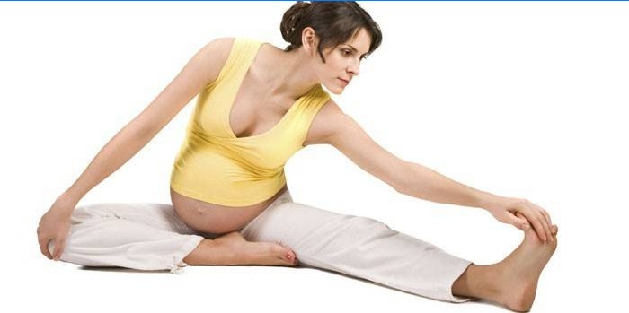 Gravid pige, der laver strækøvelser