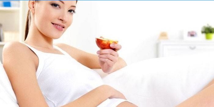 Gravid pige med æble i hånden