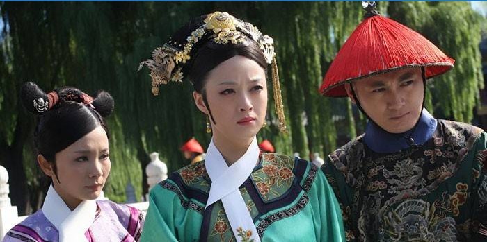 Piger og en fyr i nationale kinesiske kostumer