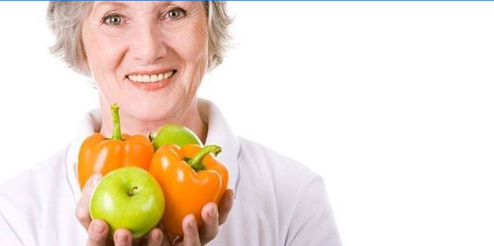 Kvinde holder æbler og peberfrugter