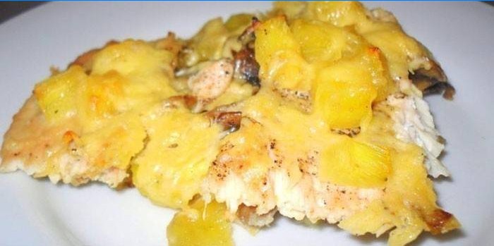 Et stykke kylling med kartofler, ananas og ost