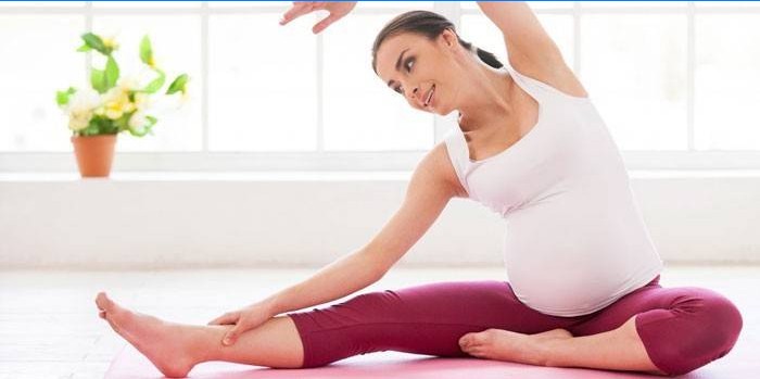 Gravid pige, der laver pilates derhjemme