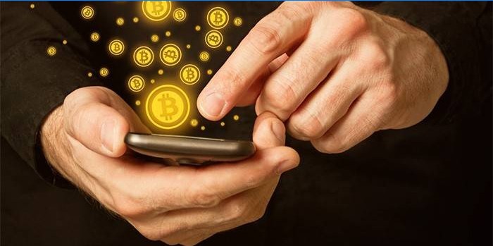 Mand med smartphone i hænder og bitcoin-ikoner.