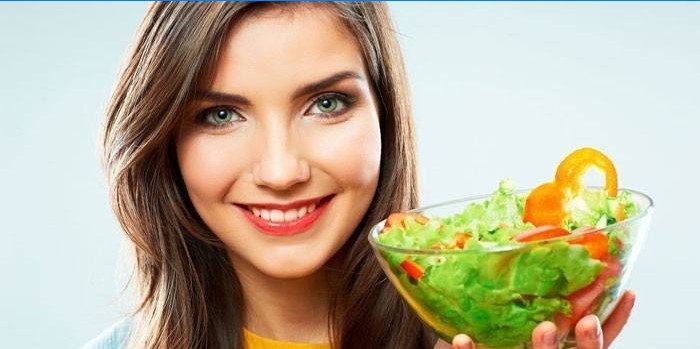 Pige holder en tallerken med salat
