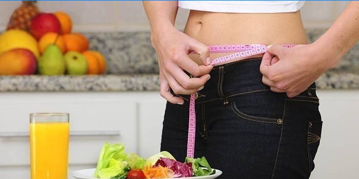 Centimeter på en kvindelig talje, grøntsagsalat og juice